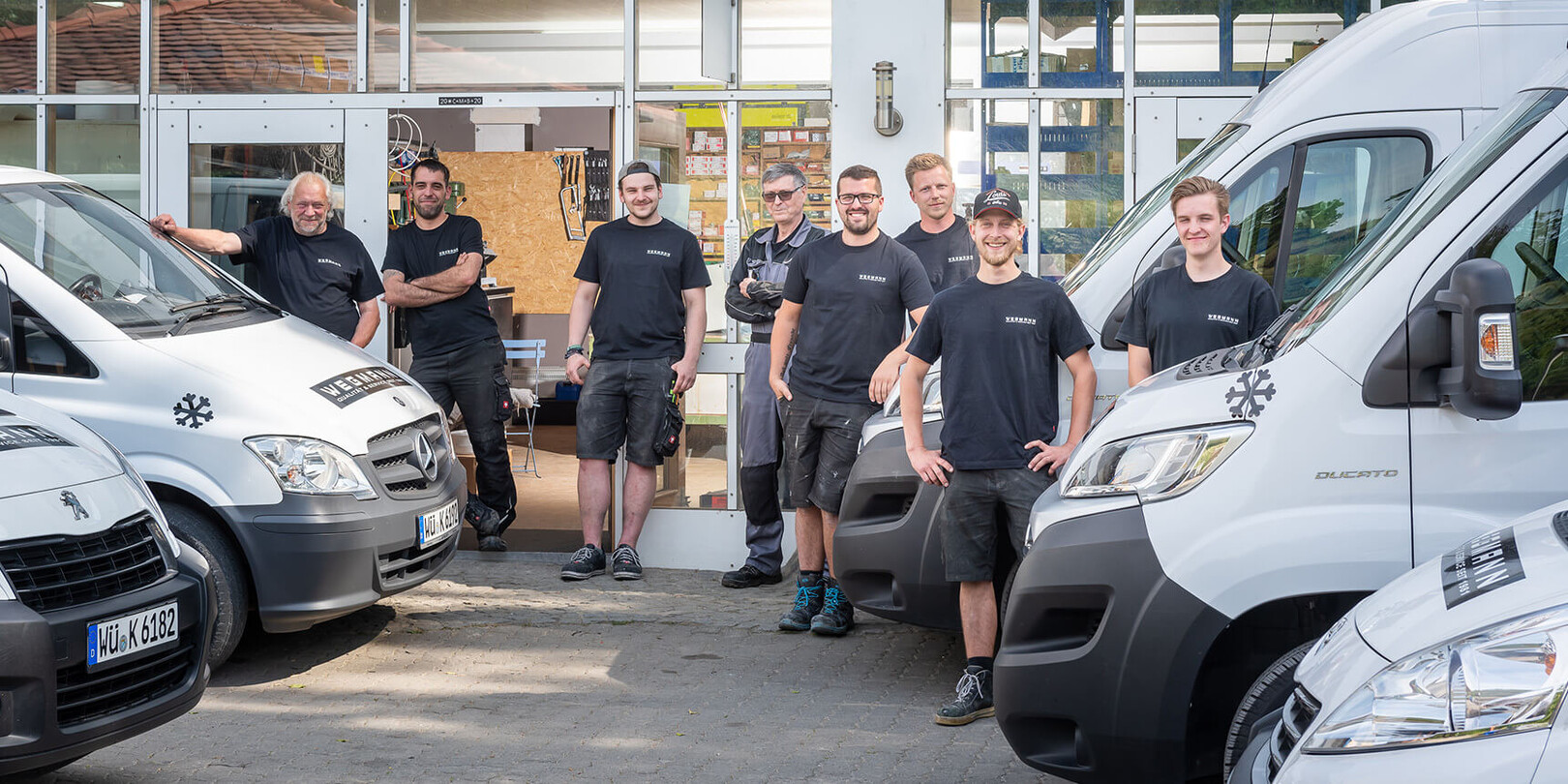 Team der Firma Wegmann Klimatechnik steht vor weißen Transportern und Firmengebäude.